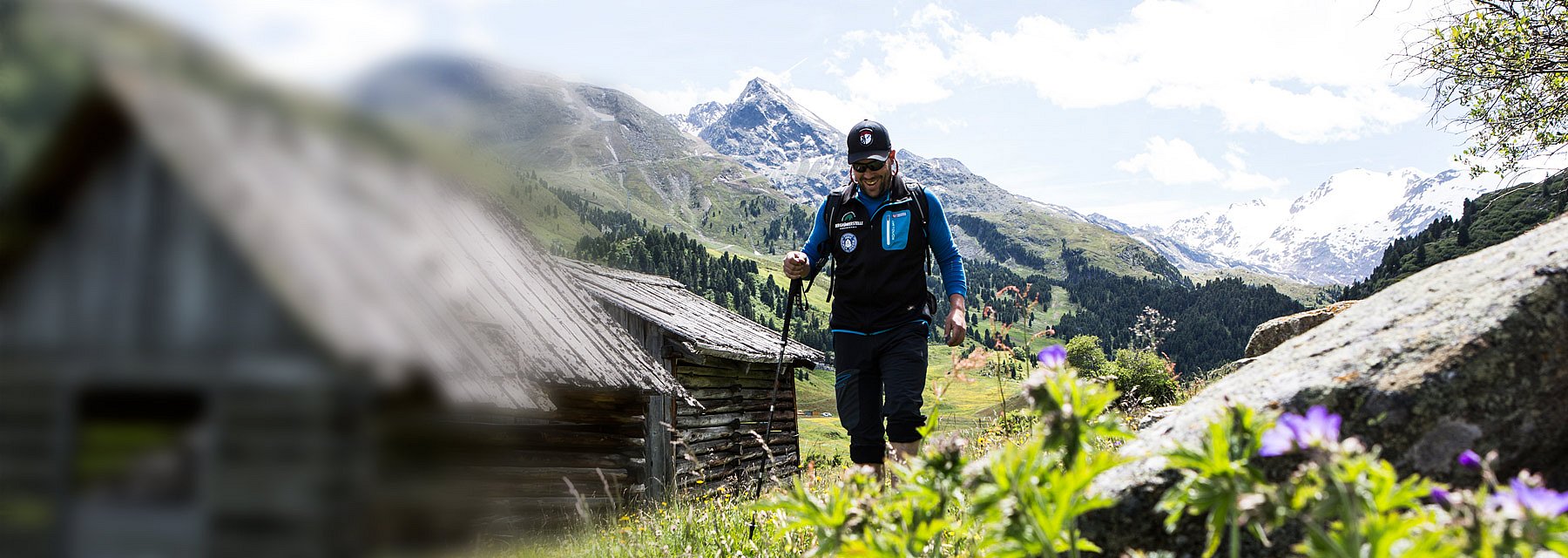 Mann wandert in der Sonne neben einer Holzhütte