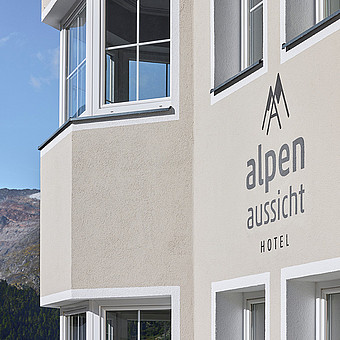 Auf dem Hotel ist die Aufschrift ' Alpenaussicht Hotel' zu sehen.
