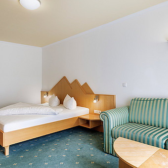 A double bed and a sofa in a hotel room.