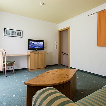 A green sofa and a television in a hotel room.