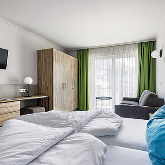 One bedroom with a large double bed, a wardrobe and a small TV.