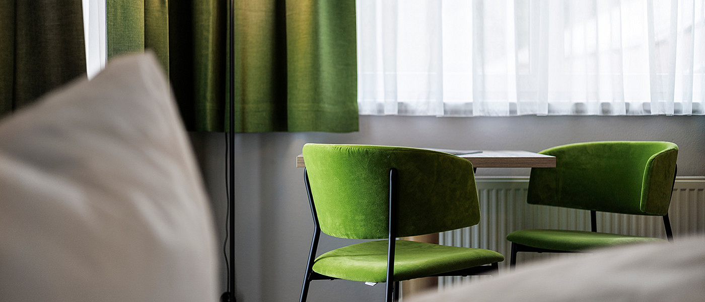 Zwei grüne Stühle stehen an einem Tisch.