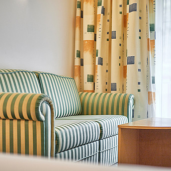 A green striped sofa in a hotel room.