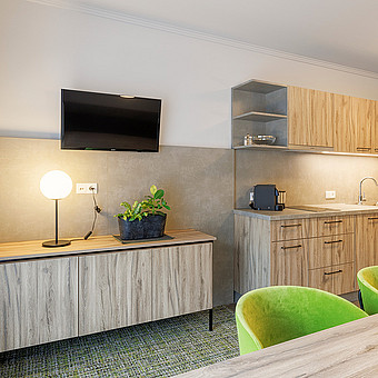 A small television hangs next to a kitchen.