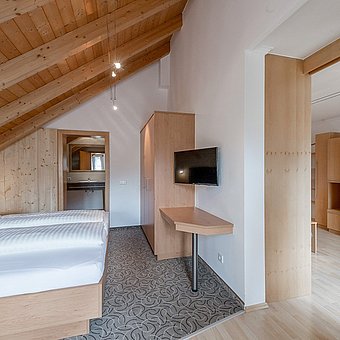 A television hangs in front of a large double bed.