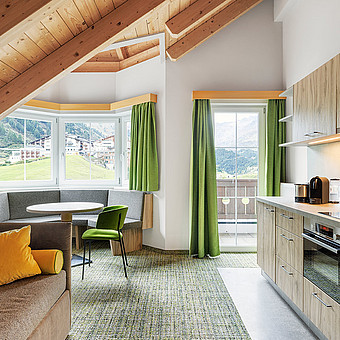 A modern flat with a small kitchen and a round dining table.