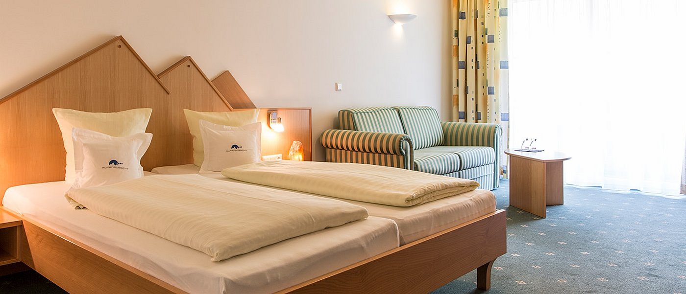 Gemütliches Hotelzimmer mit Doppelbett und Couch.