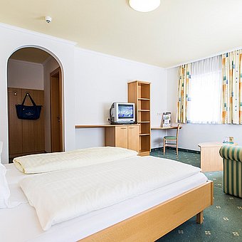 Doppelbett, Sofa und Fernseher in einem Hotelzimmer.
