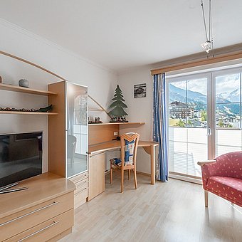 A desk and a large television in a hotel room.