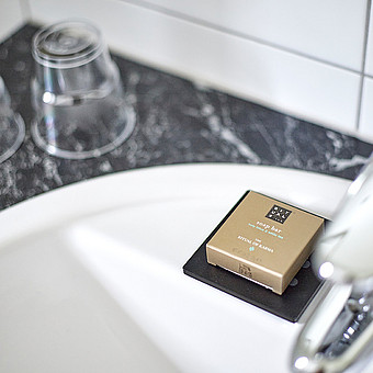 Eine verpackte Ritual Seife liegt bei einem Waschbecken.