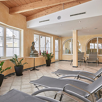 In einem Raum stehen Sonnenliegen vor einer großen Buddhastatue.