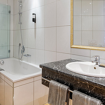 In one bathroom there is a bathtub next to a washbasin.