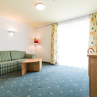 A green sofa and a television in a hotel room.