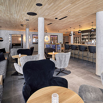 Eine Bar umgeben von runden Tischen und Samtsesseln.