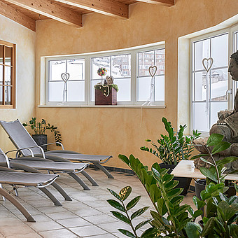 In einem Raum stehen Sonnenliegen und eine große Buddha Statue.