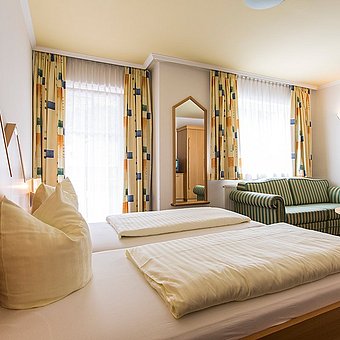 Ein großes Doppelbett und ein grünes Sofa in einem Hotelzimmer.