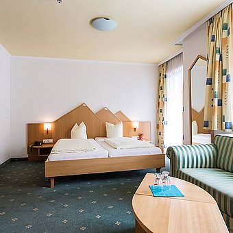Doppelbett, Sofa und Fernseher in einem Hotelzimmer.